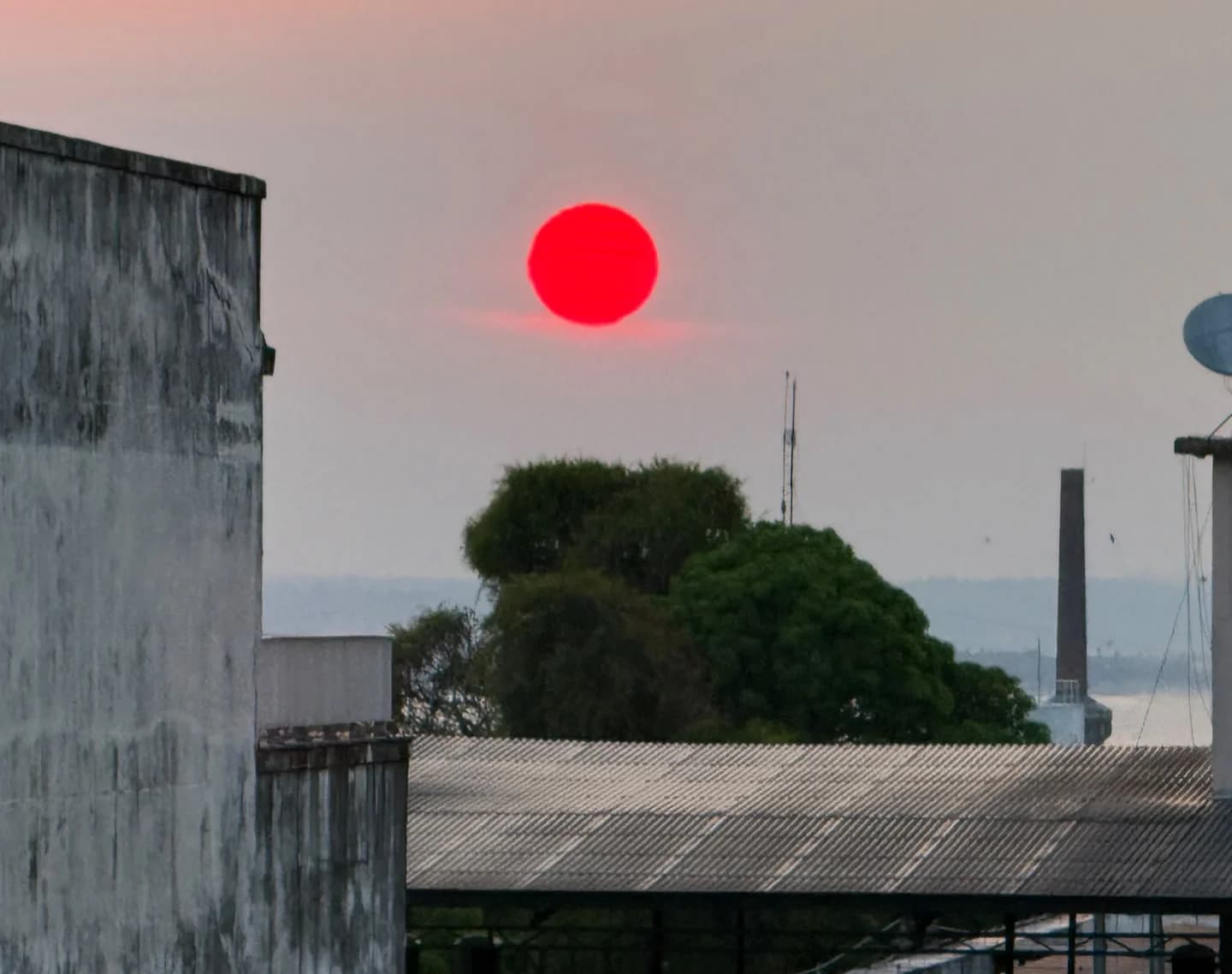 Sol avermelhado em céu encoberto por fumaça das queimadas