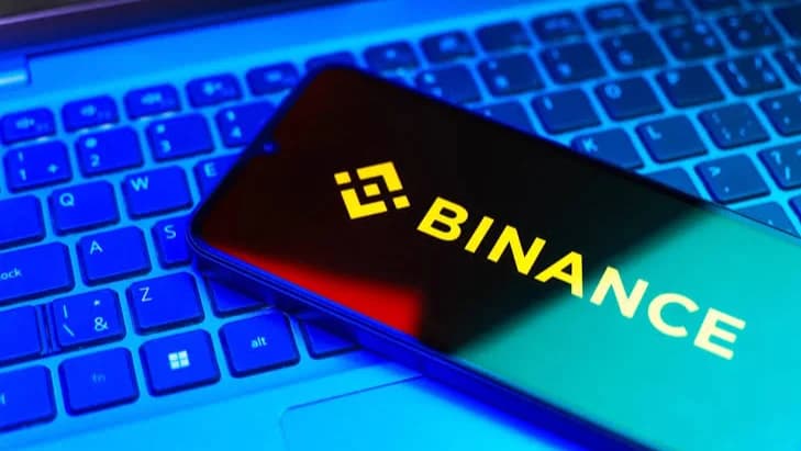 Celular com o logotipo da Binance sobre o teclado de um notebook
