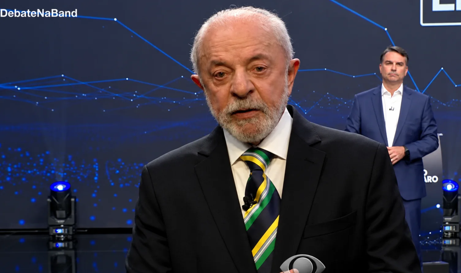 Lula fala durante debate na Band, com Flávio Bolsonaro ao fundo