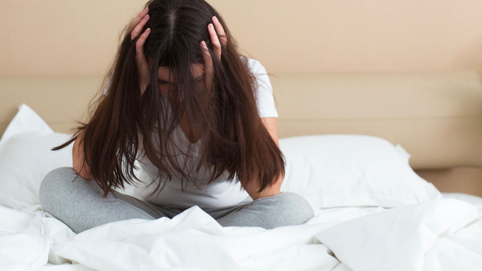 Mulher com traumas sentada em sua cama.