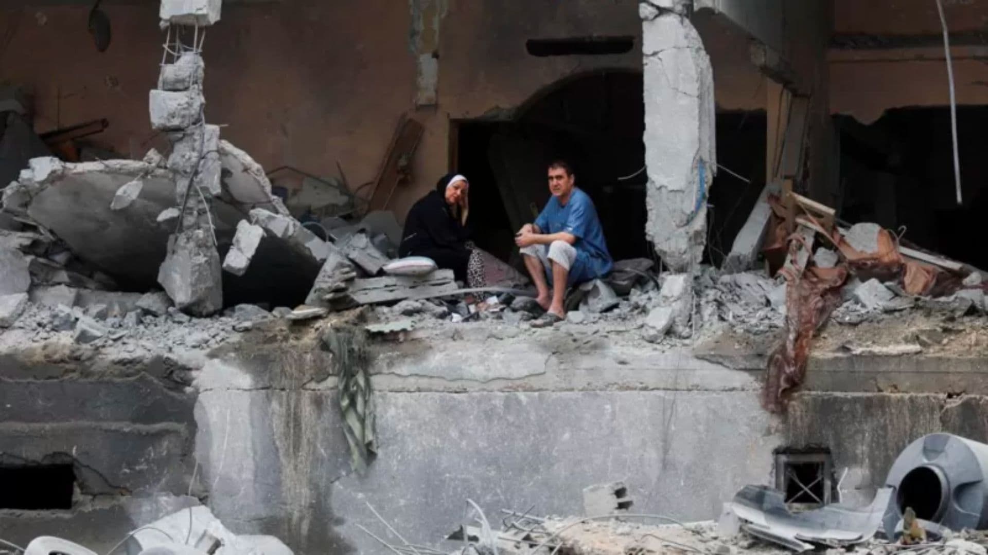 Palestinos sentam-se entre os escombros de um prédio residencial danificado, após os ataques israelenses, na Cidade de Gaza.