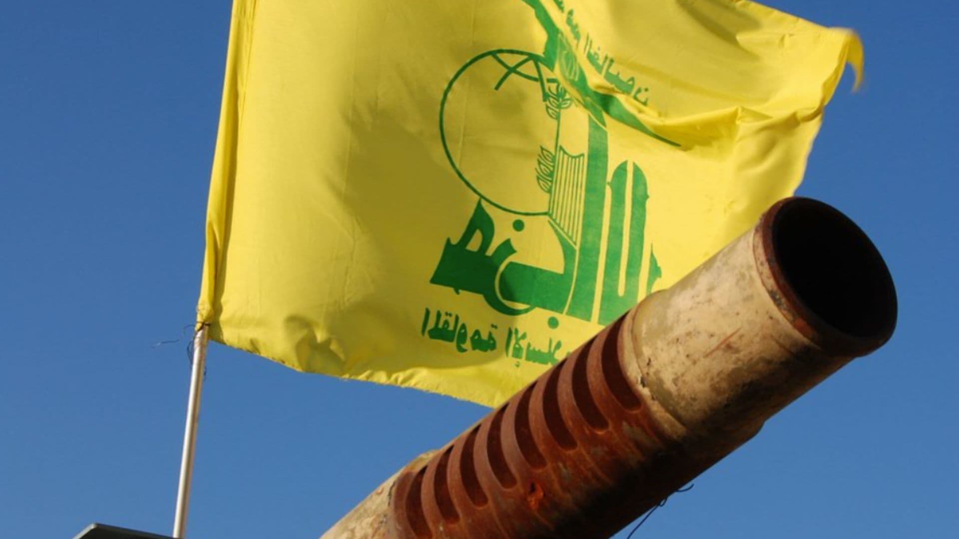 Bandeira da organização terrorista Hazbollah junto a um canhão