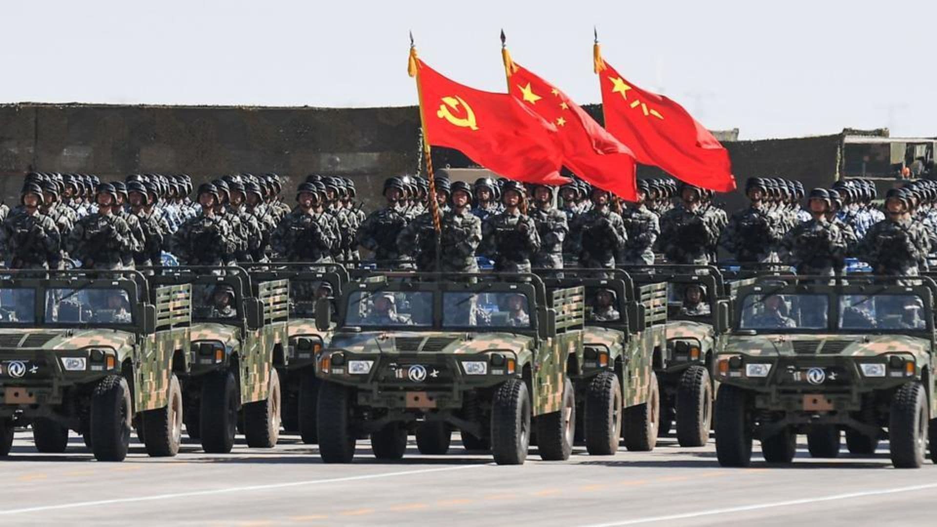 Militares chineses dentro de veículos com bandeiras do Partido Comunista Chinês, do país e do Exército de Libertação Popular.