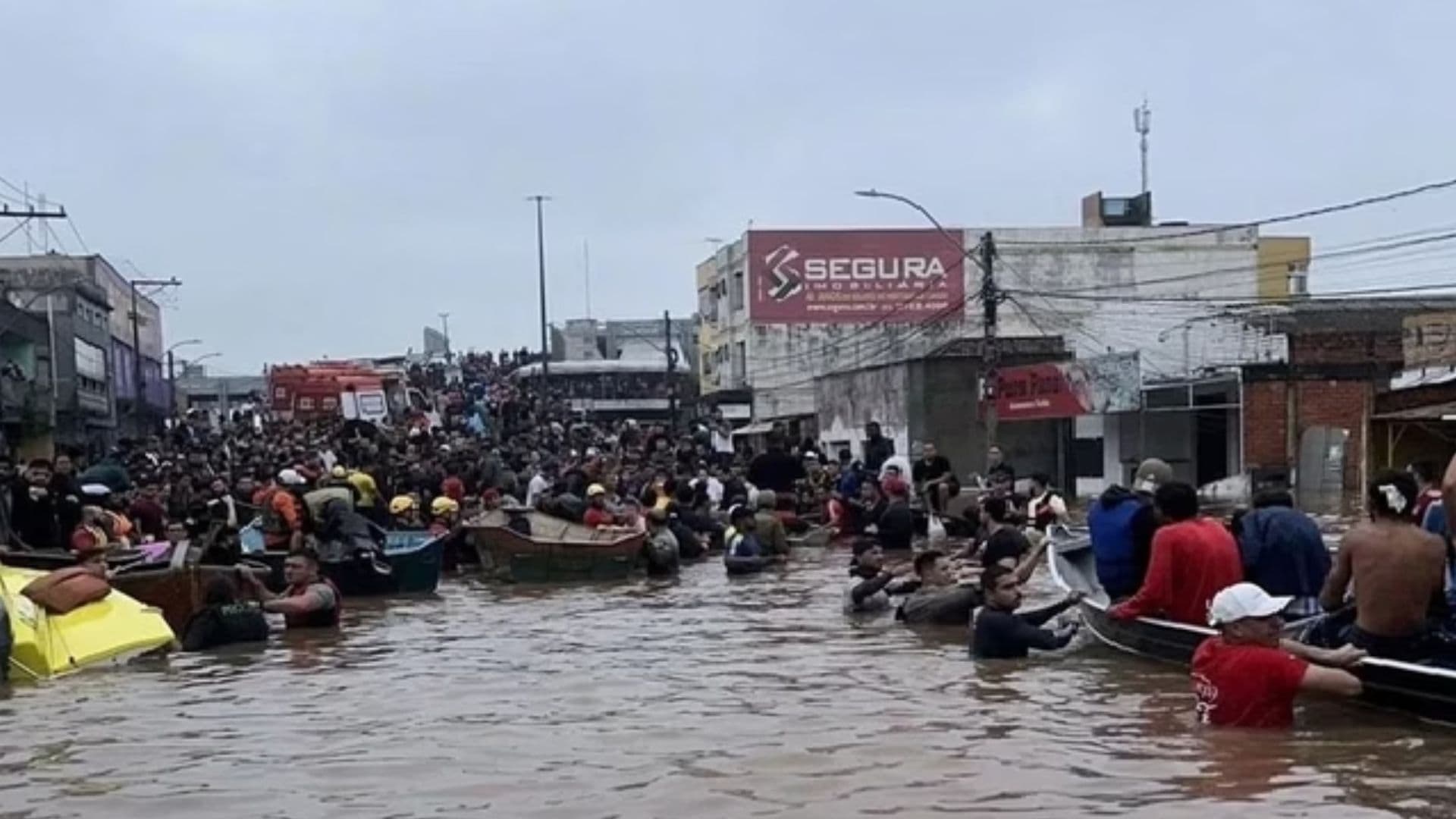 Grupo de pessoas com barcos ajuda a tirar pessoas de locais inundados no Rio Grande do Sul