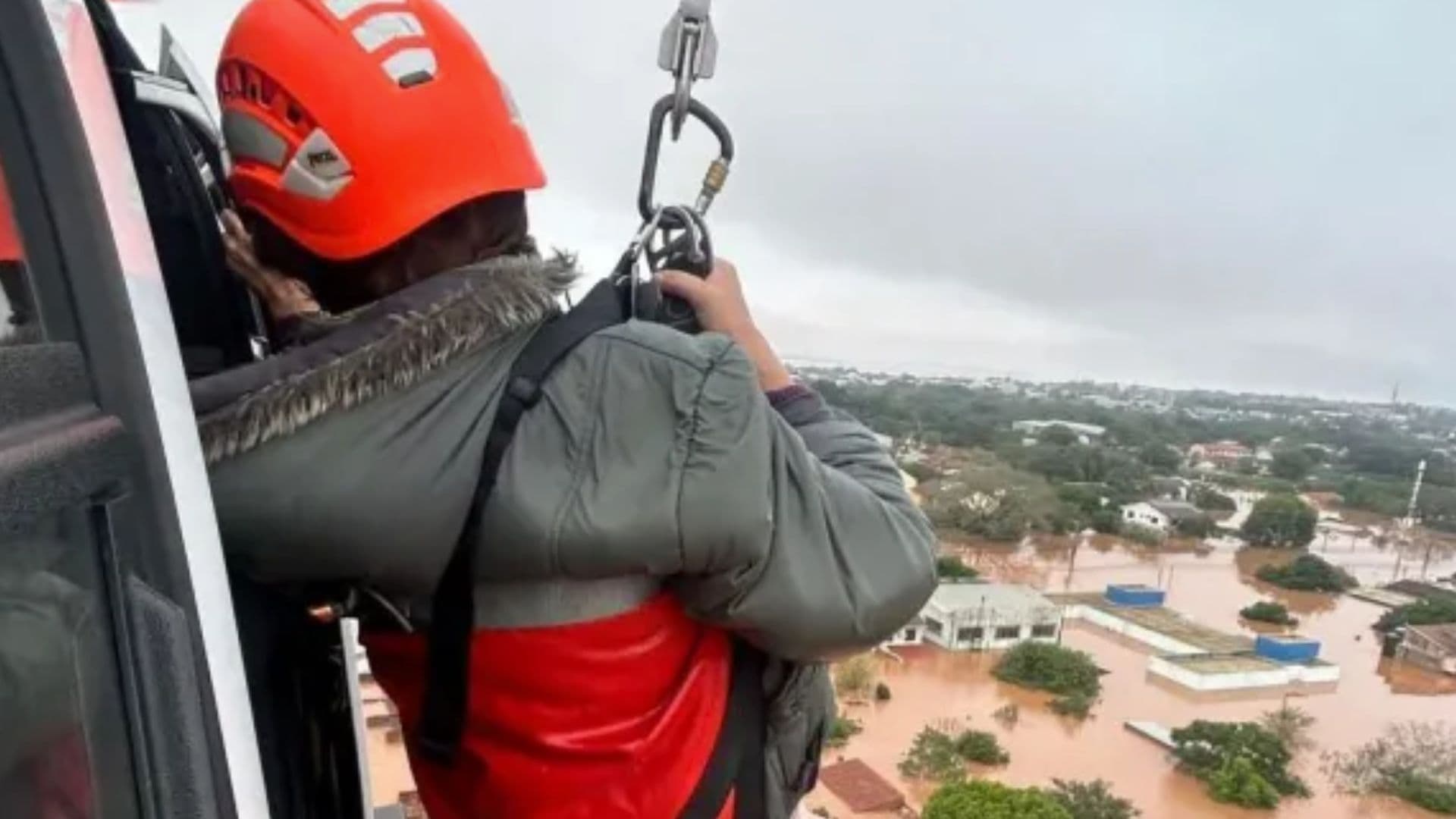 Policial içado por corda observa área inundada