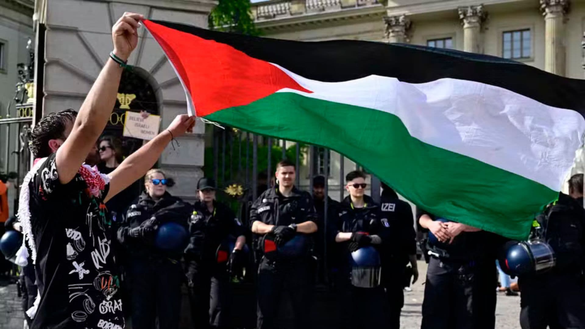 Estudante segurando bandeira palestina em meio a protestos em universidades nos eua.