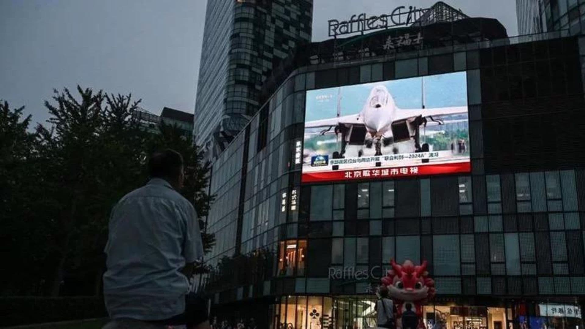 Cidadão de Taiwan vendo o anúncio do Ministério da Defesa de que aviões chineses foram detectados durante manobras.
