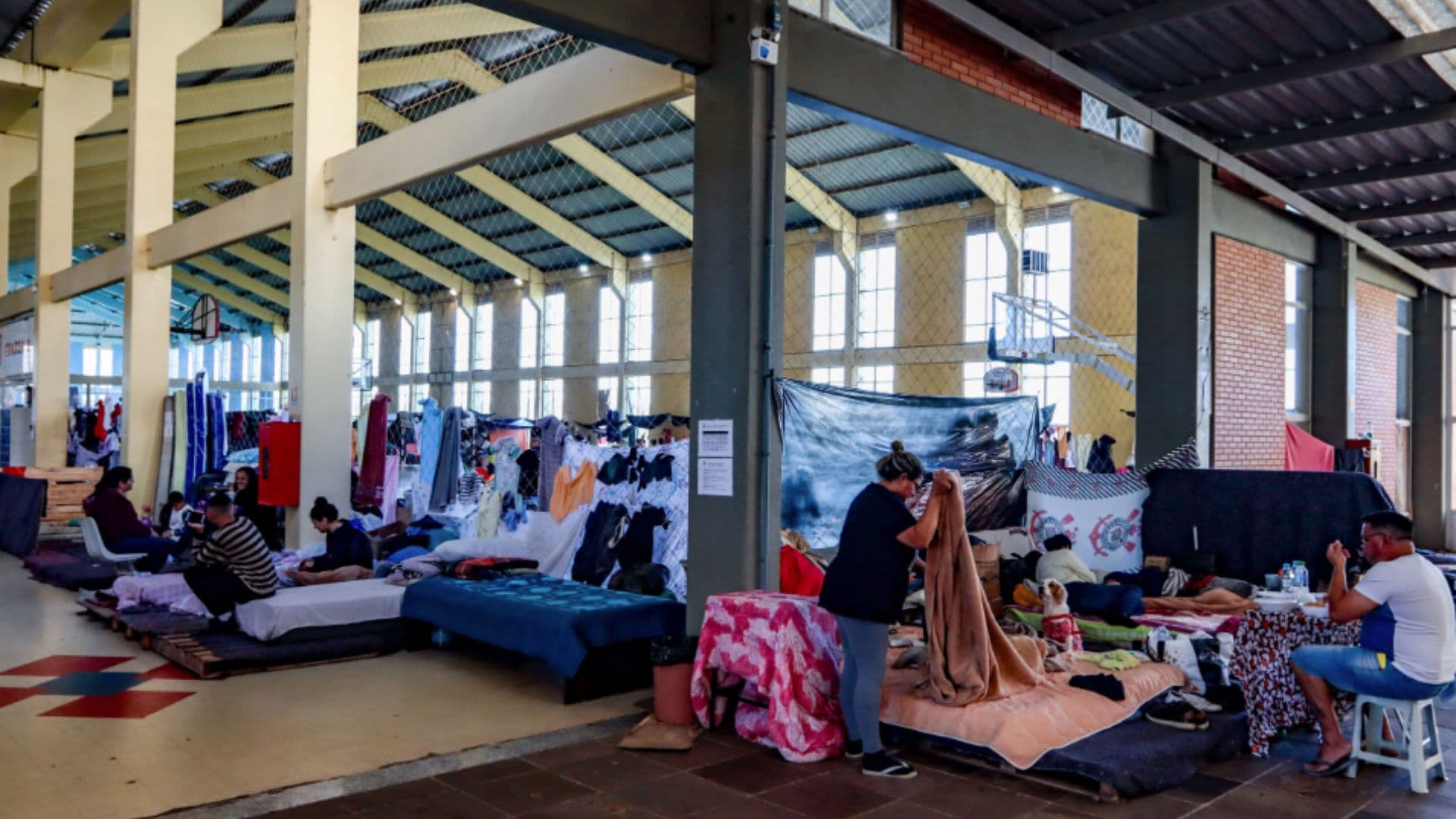 Abrigados arrumam suas camas em abrigo no RS