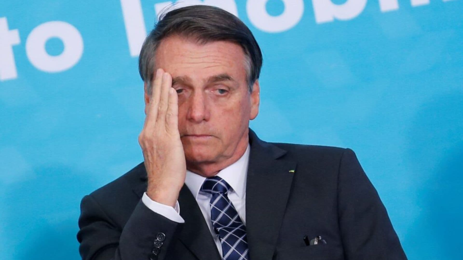 Jair Bolsonaro esfrega o rosto com expressão de preocupação.