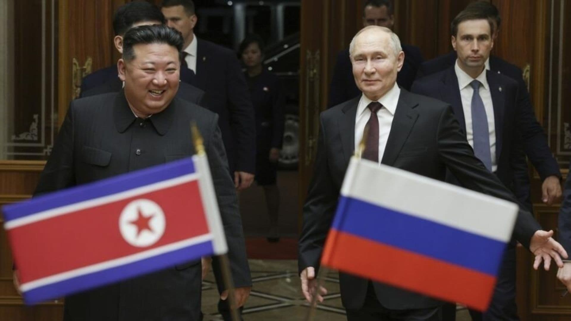 Kim Jong-Un e Putin entrando em uma sala de conferencia, na imagem é possível ver os dois alinhados às bandeiras de seus respectivos países.