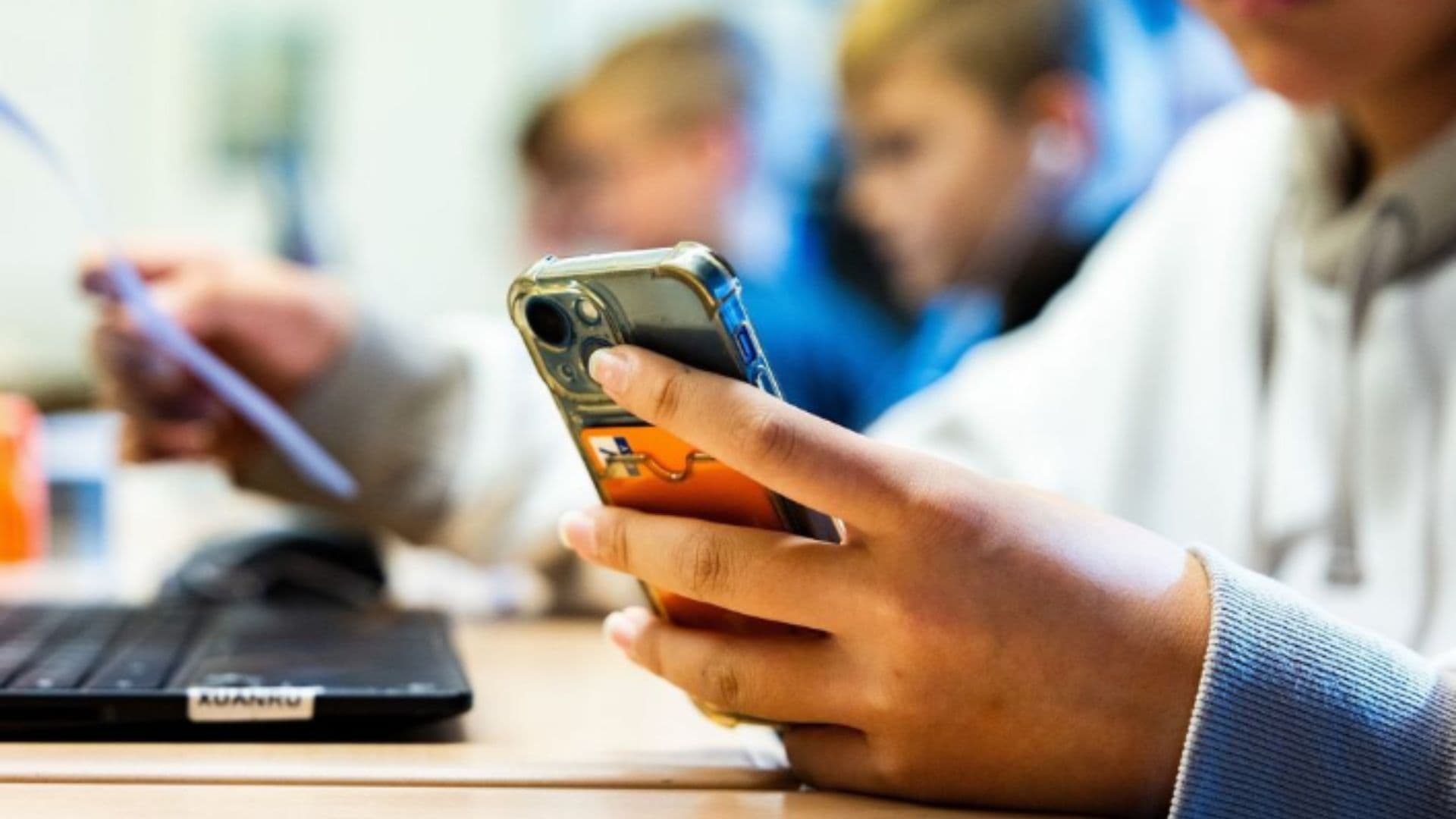 Criança usa o celular em sala de aula