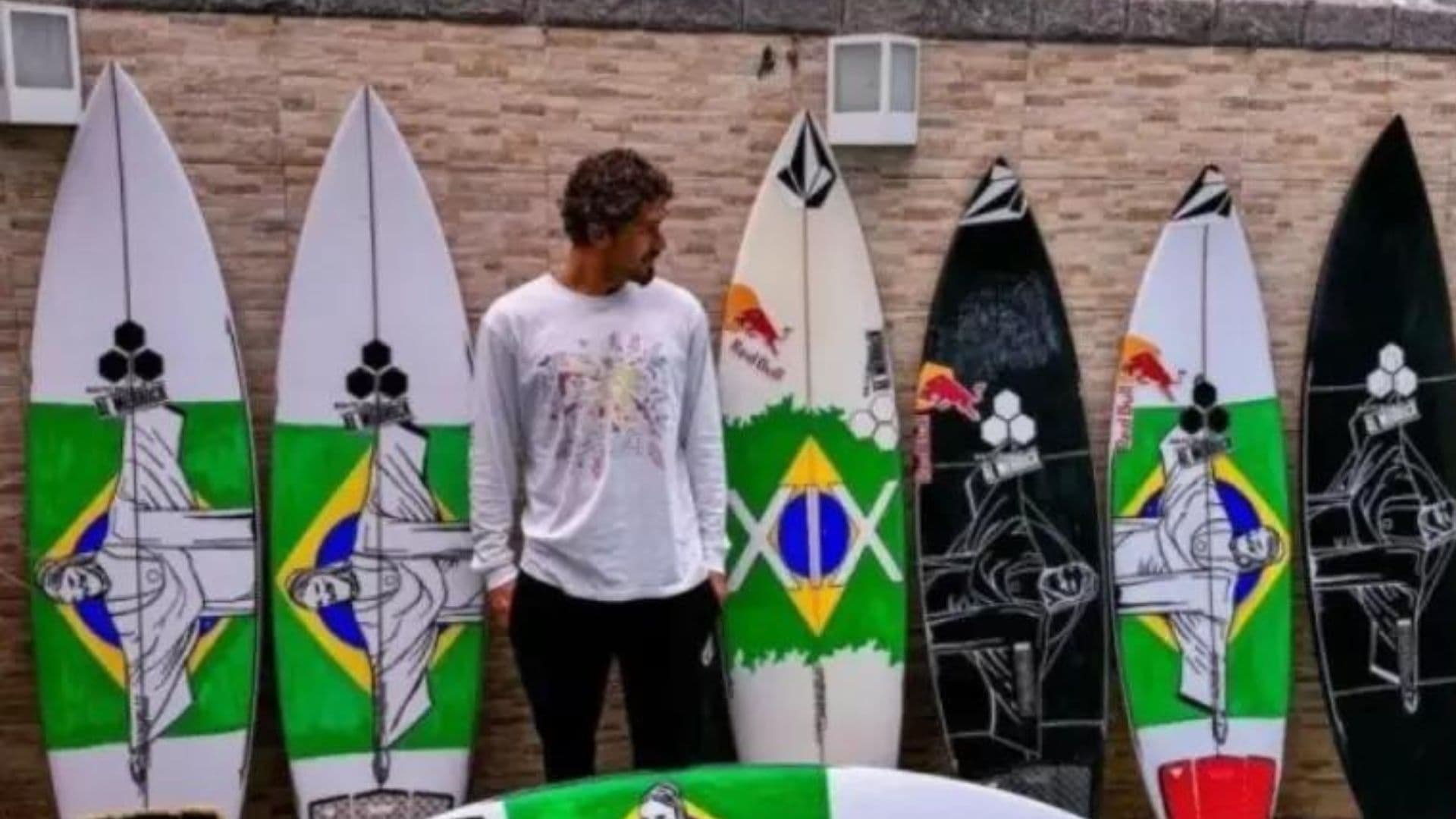 O surfista João Chianca, conhecido como Chumbinho, ao lado de suas pranchas pintadas com a imagem do Cristo Redentor.