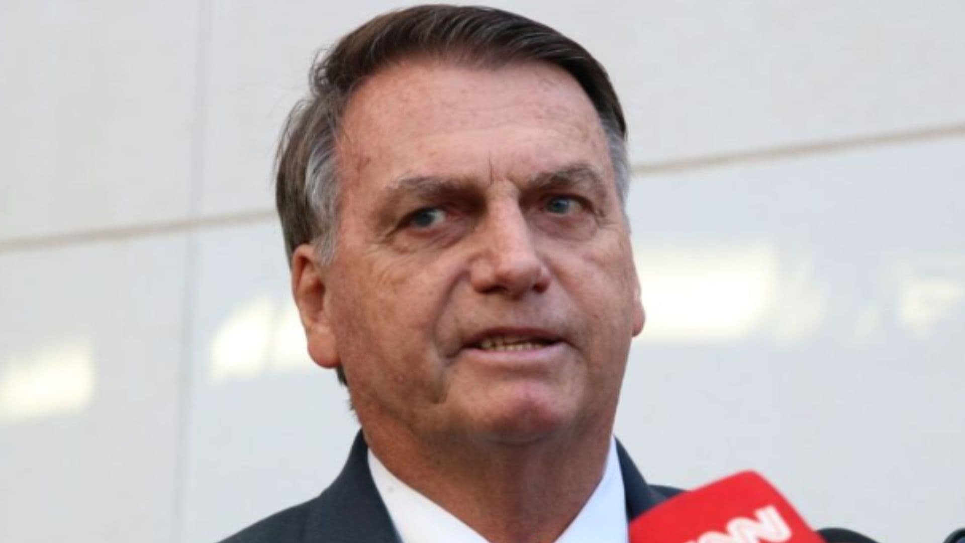Bolsonaro Comenta “Derrotamos O Bolsonarismo” De Ministro. Bolsonaro aparece em frente à microfones durante entrevista. Ele usa terno e gravata