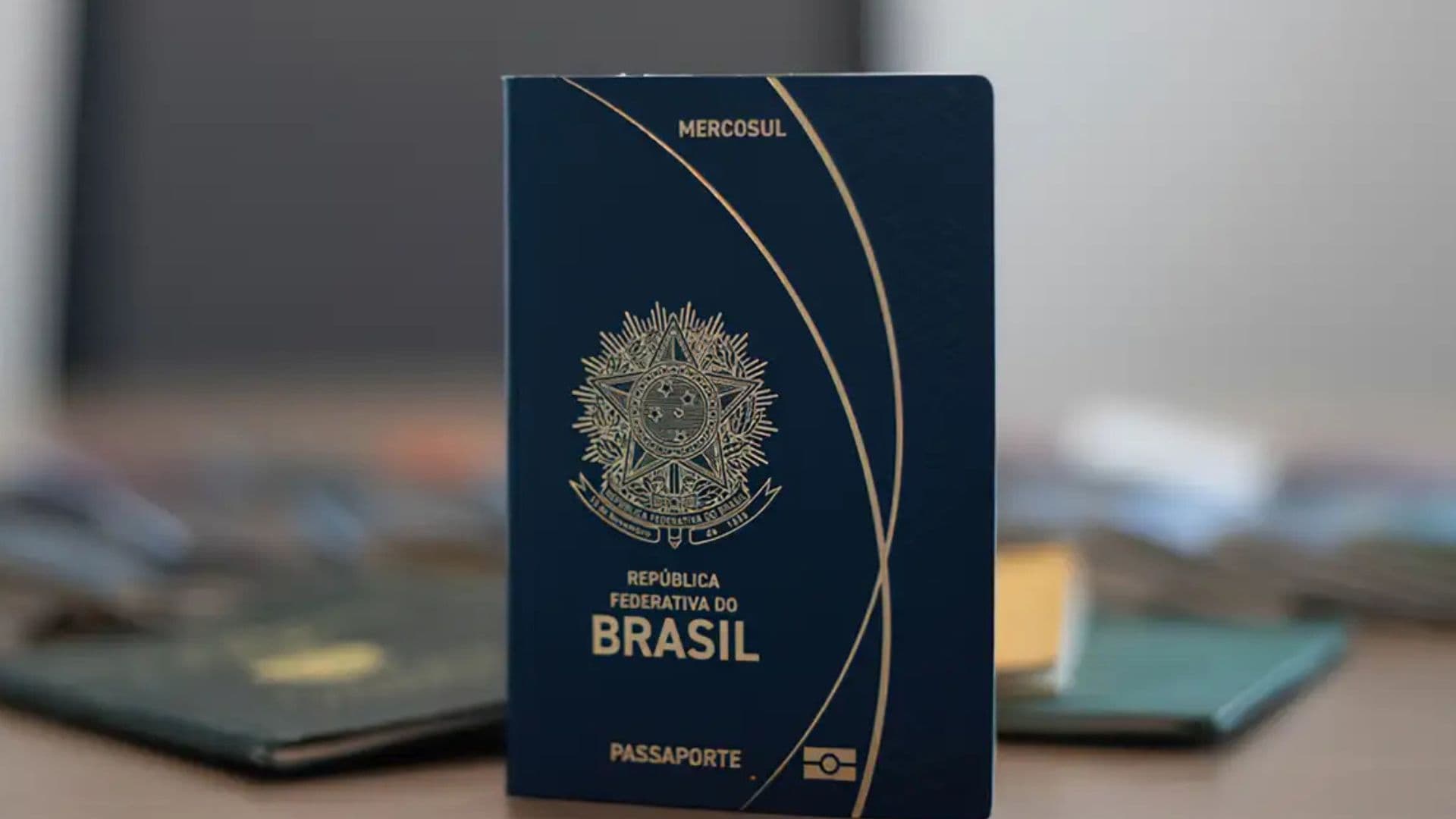 Foto de passaporte brasileiro em cima de uma mesa de madeira. Entenda se brasileiros foram deportados do Reino Unido