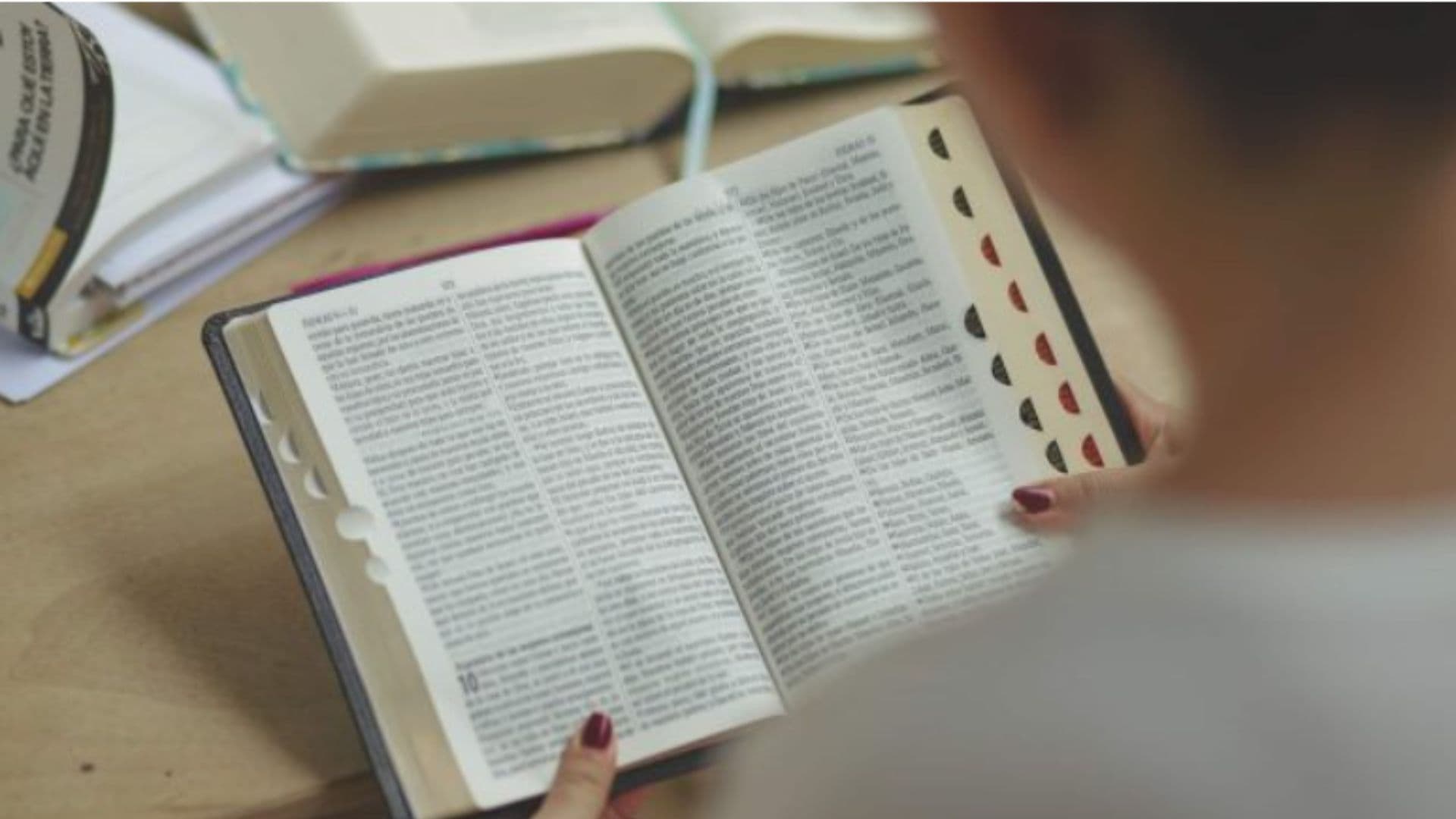 Bíblia aparece na mão de uma mulher. O livro está sobre uma mesa de madeira. Jovens fazem vendas de Bíblias disparam nos EUA