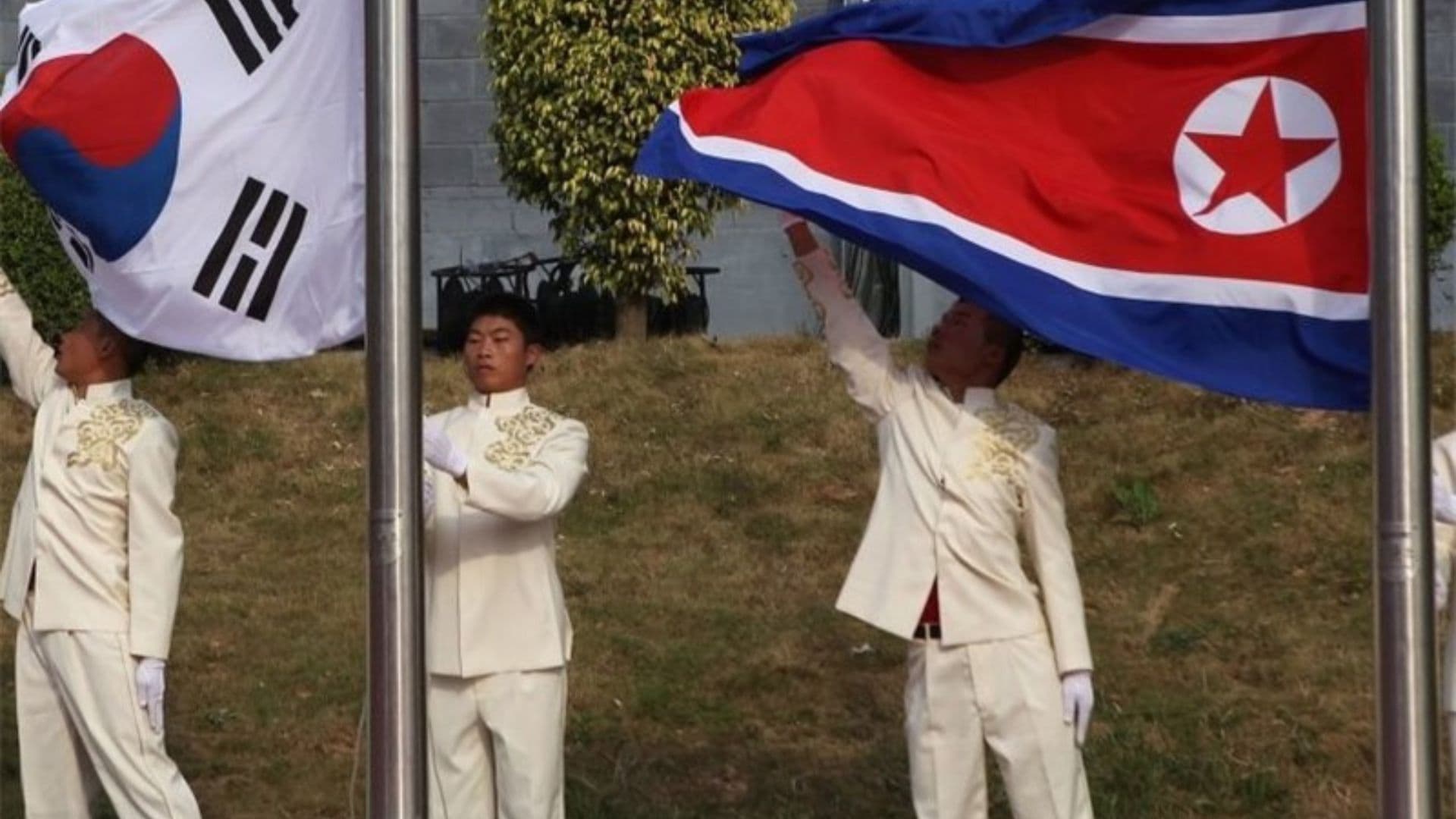 Bandeiras da Coreia do Norte e da Coreia do Sul sendo erguidas