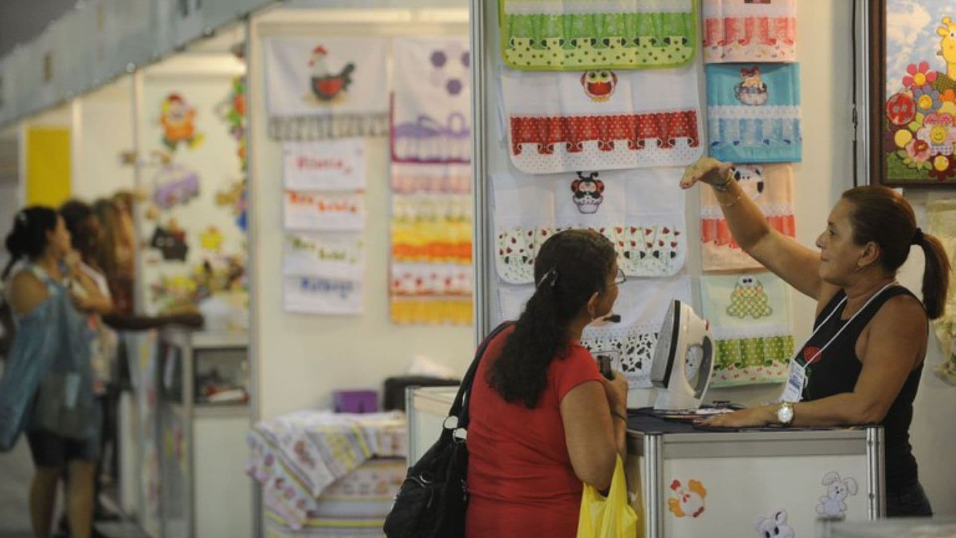 Uma pequena empresária conversando com um cliente em uma lojinha de panos.