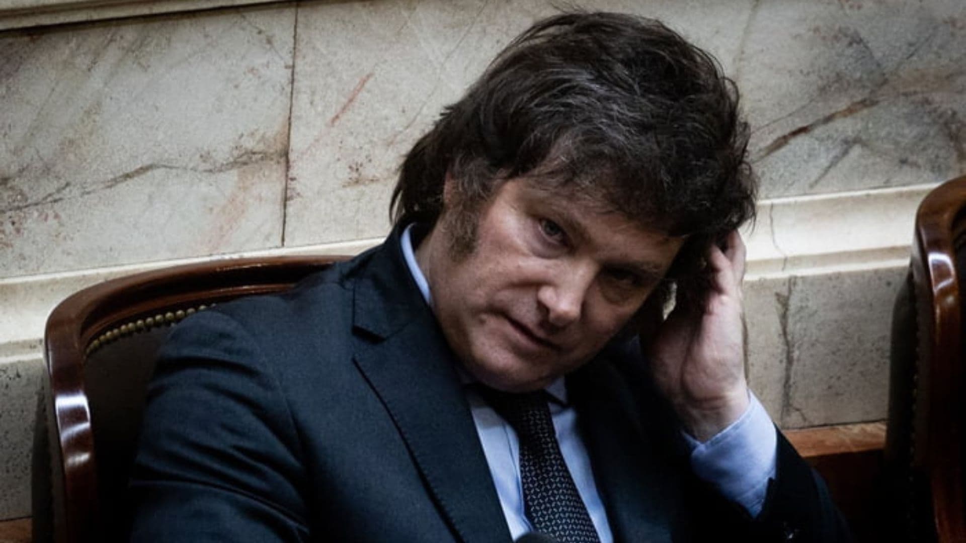 Javier Milei apoiando a cabeça com cara de preocupação.