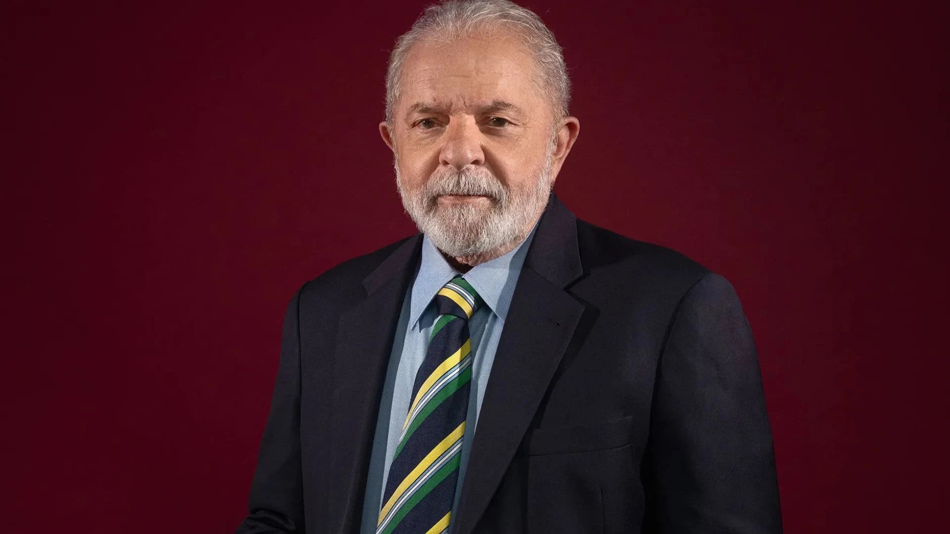 Lula com gravata com as cores do Brasil e fundo vermelho