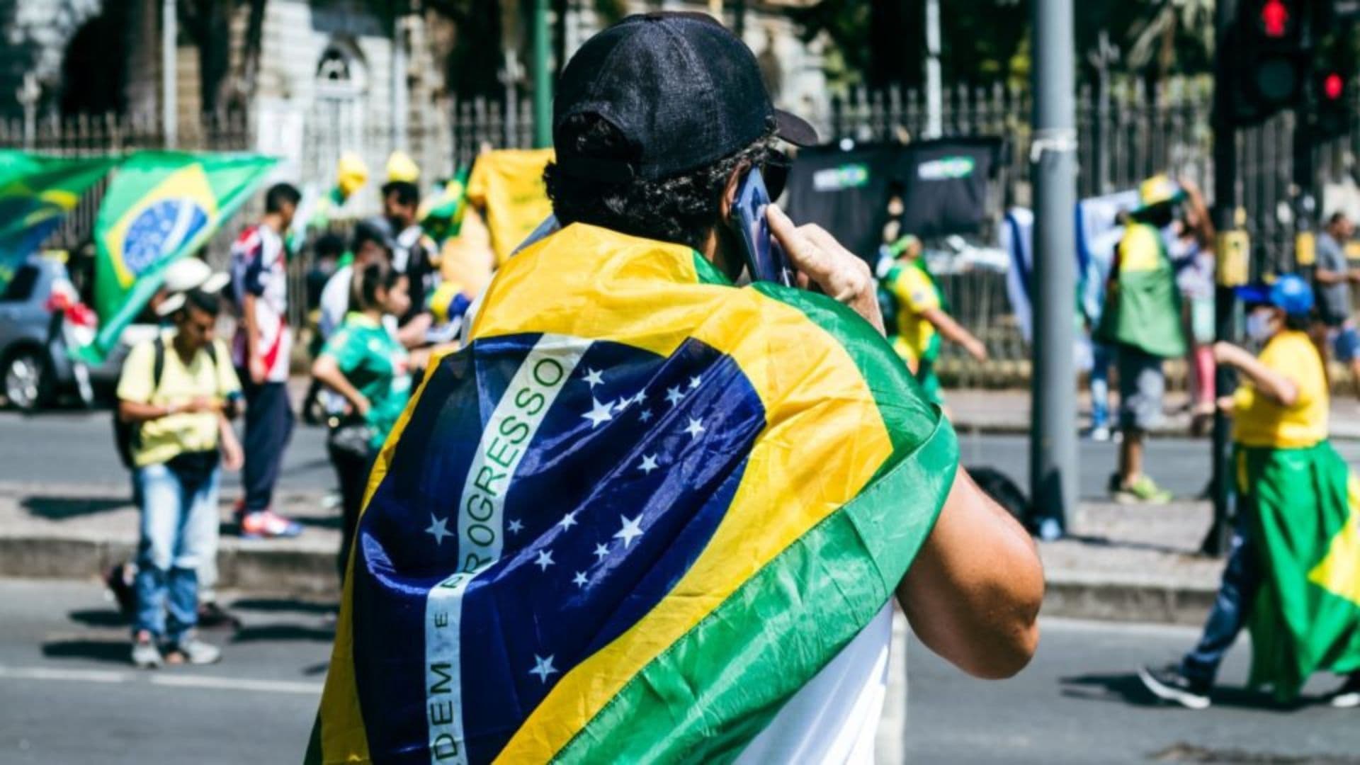 Homem durante manifestação com bandeira do Brasil nas costas.