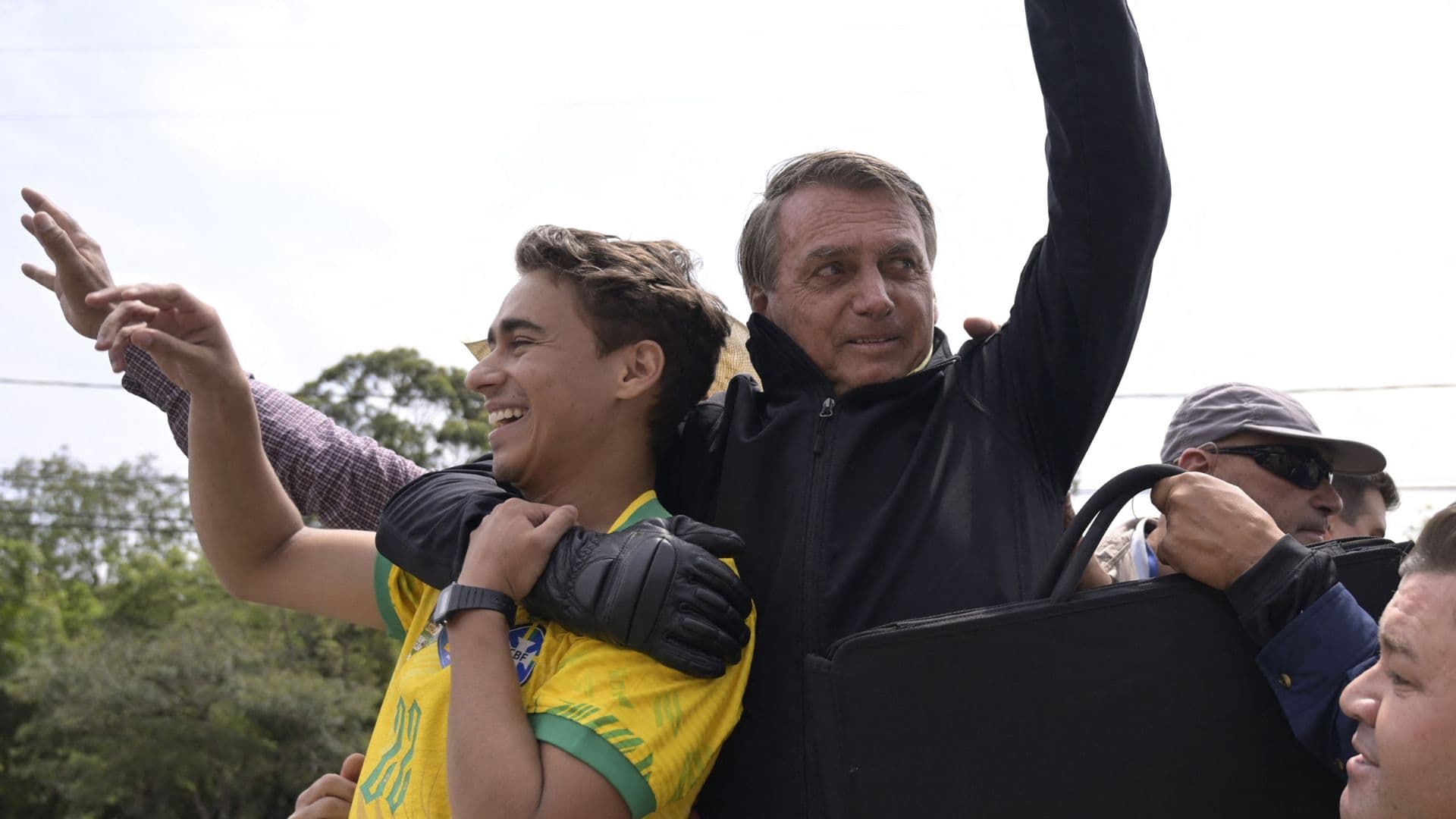 Jair Bolsonaro e Nikolas se abraçam durante manifestação.