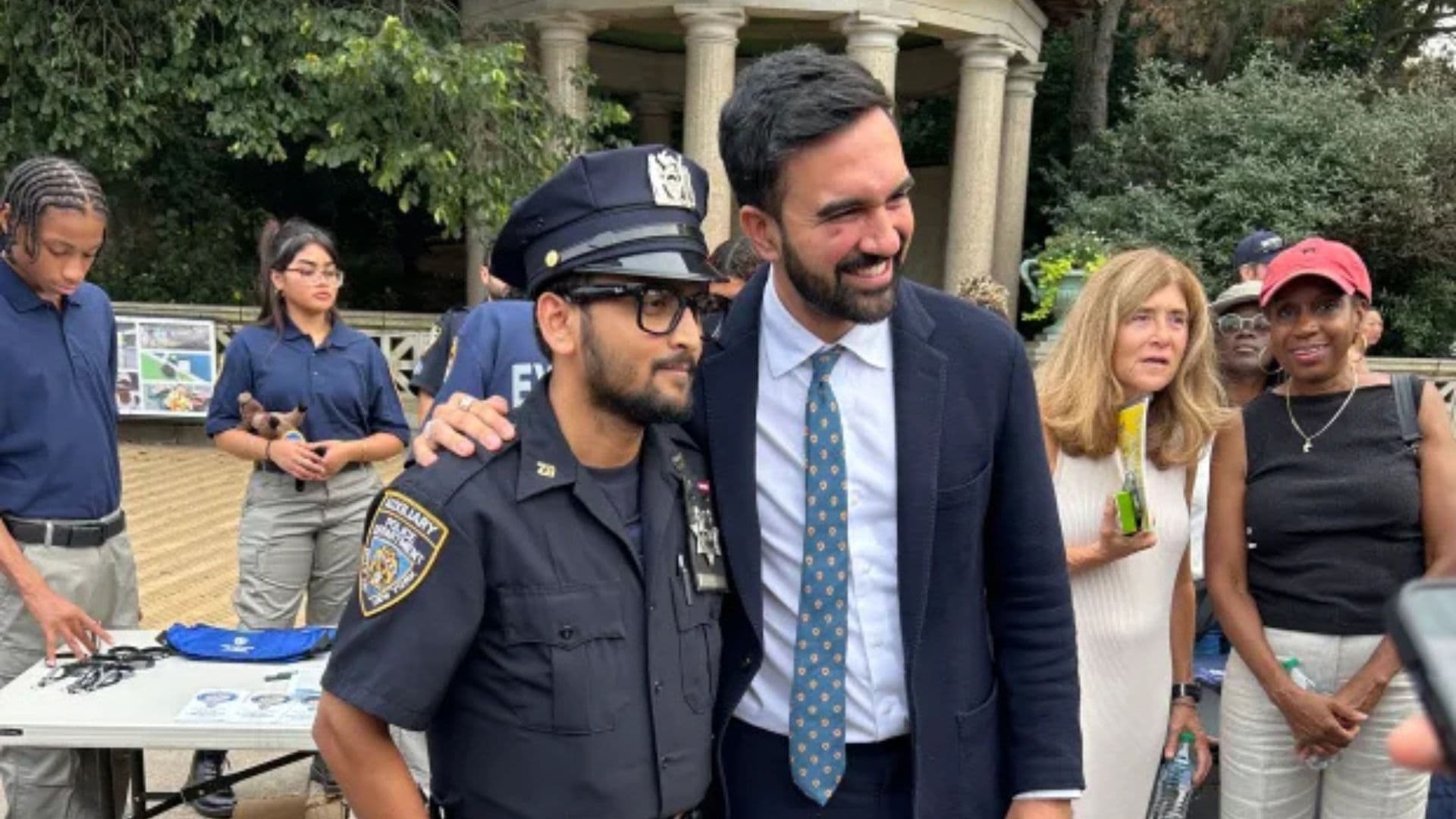 Mamdani abraçado com um policial, prefeito fala contra polícia, o que tem causado demissões.