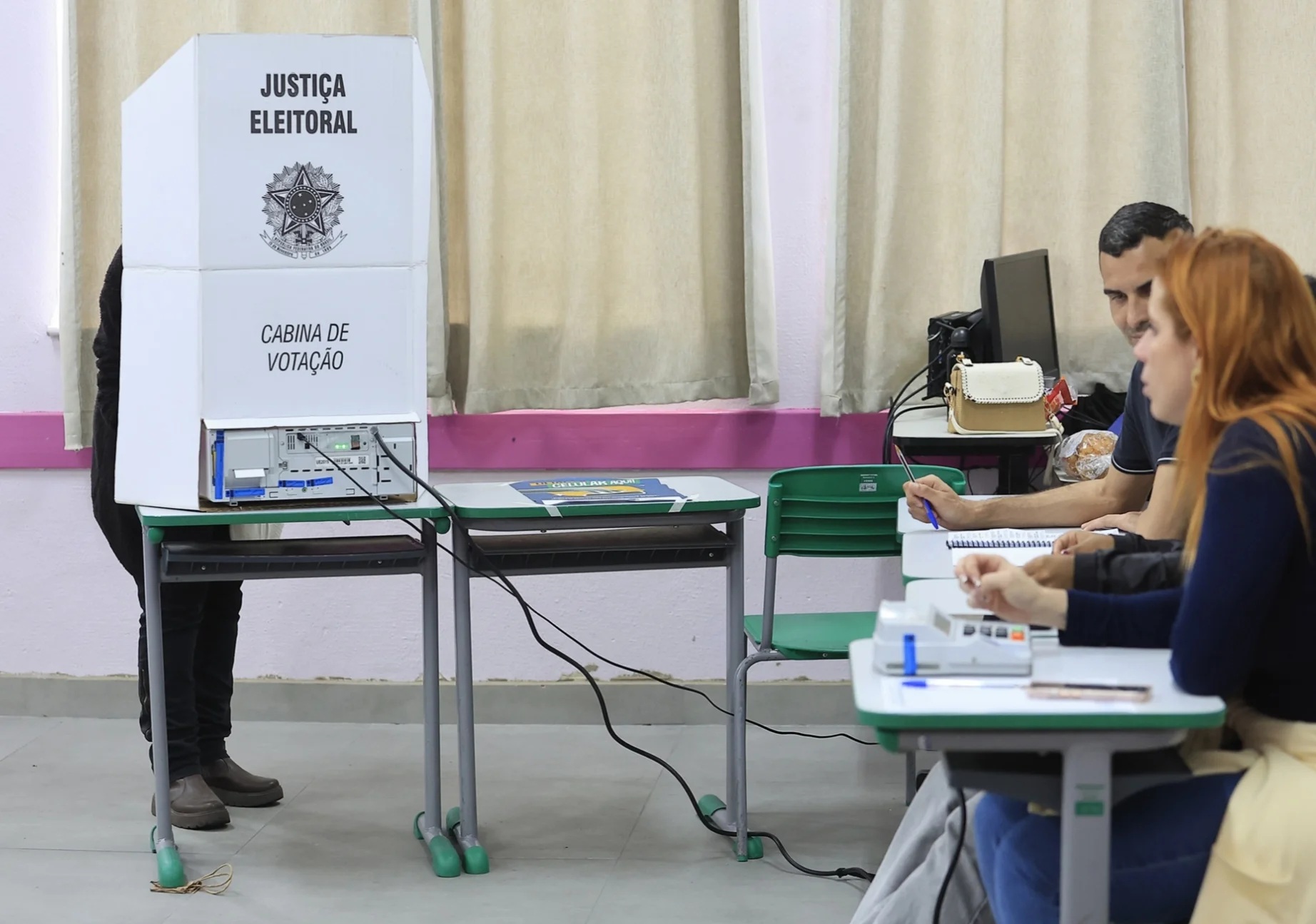Cabina de votação e mesários em seção eleitoral