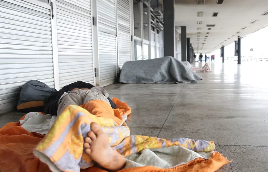 Pessoa em situação de rua dormindo sob cobertores